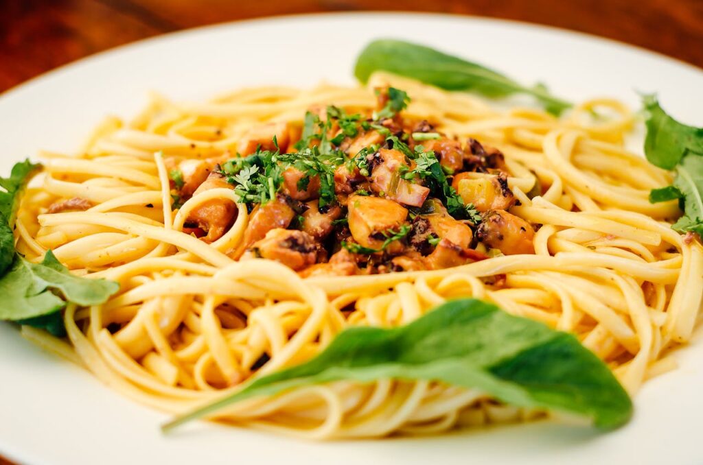 a plate of pasta with a small portion of veggies.